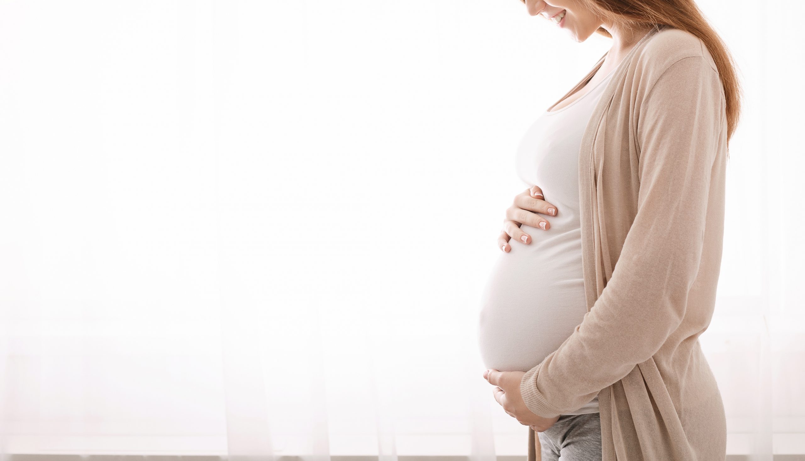 Beautiful pregnant woman hugging her tummy