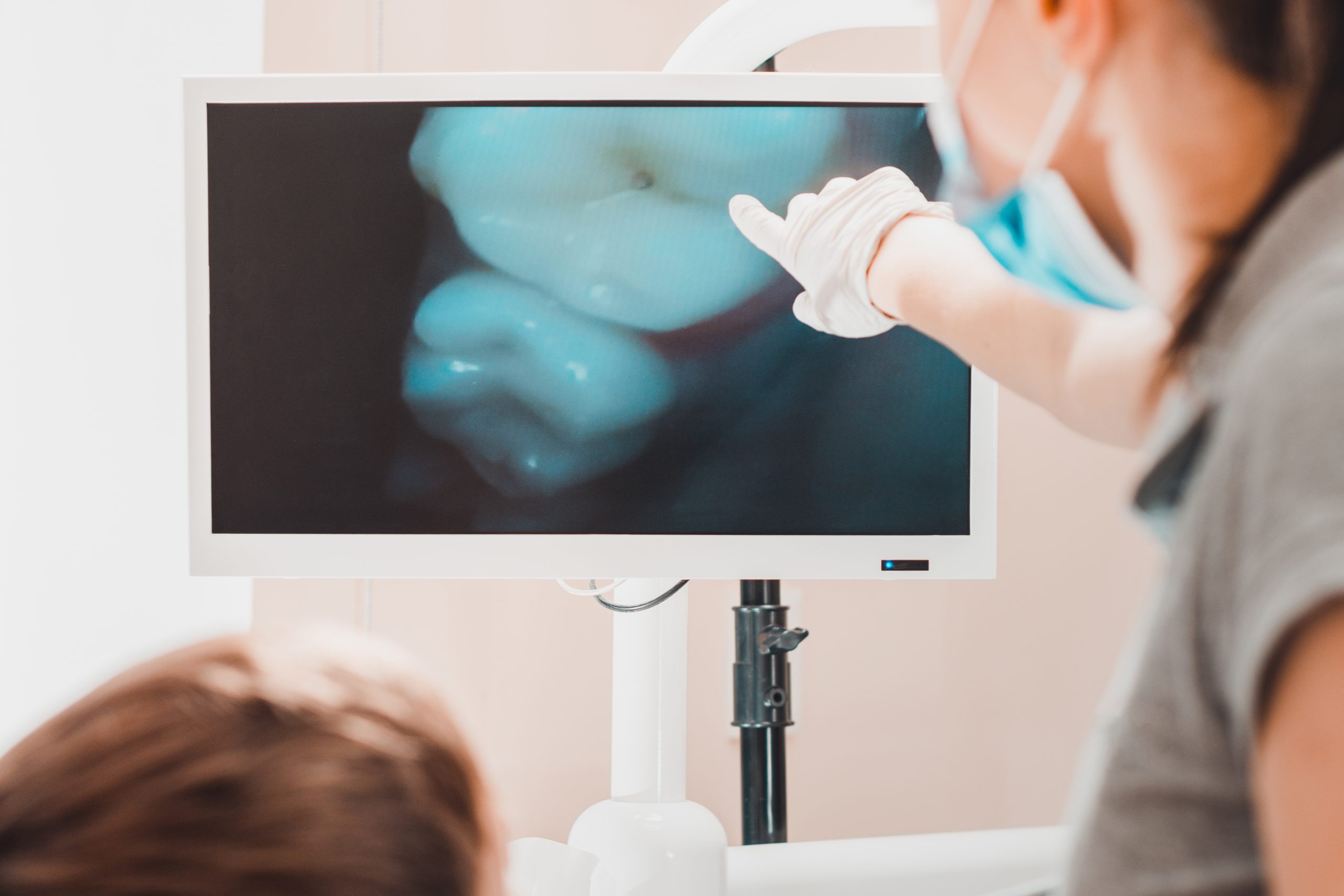 A young female dentist examines the teeth of a boy sitting in a dental chair